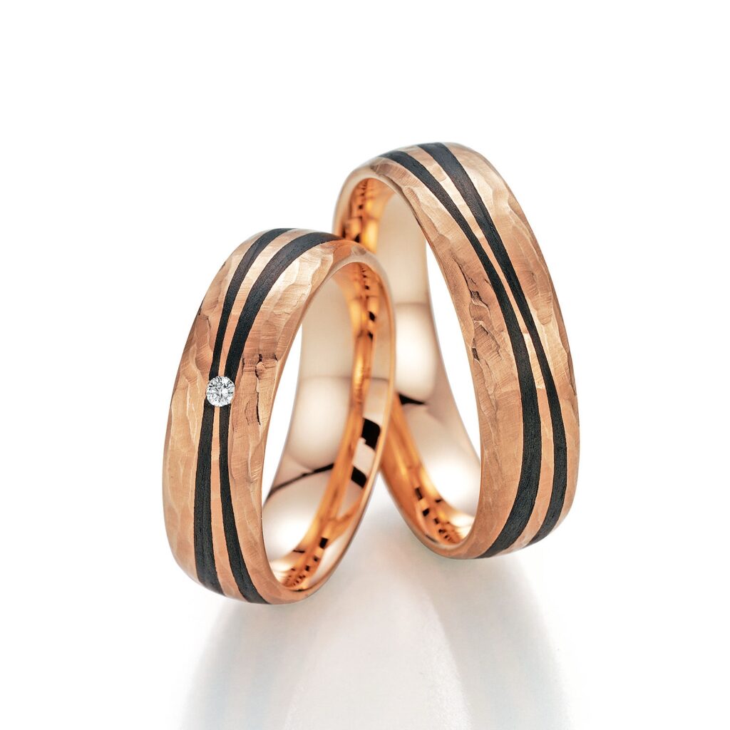 Trauringpaar in Rotgold, breit, matt, gehämmert, Inlay zwei Bahnen Carbon geschwungen, 1 Brillant 0,02 ct., Hersteller Fischer, Artikelname We said yes